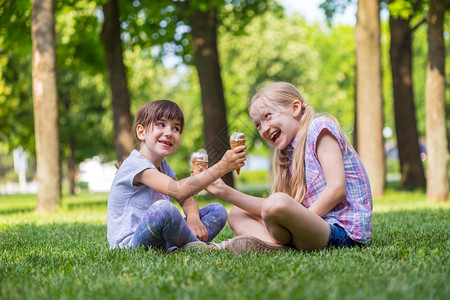 孩子假期在草原上玩可爱的小孩子们在草坪上吃奶油高清图片素材