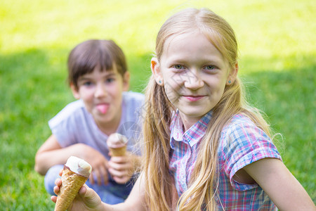孩子假期在草原上玩可爱的小孩子们在草坪上吃奶油高清图片素材