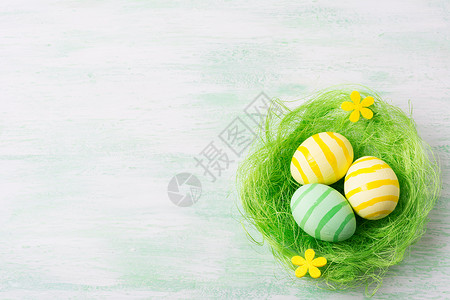 黄色彩蛋东边快乐的问候背景绿巢复制空间内有条纹彩蛋和黄花背景