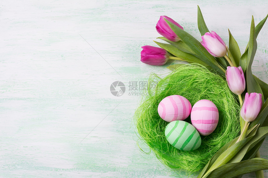 东面背景在巢穴和郁金香中涂有绿色和粉条纹的彩蛋快乐东面贺卡复制空间图片