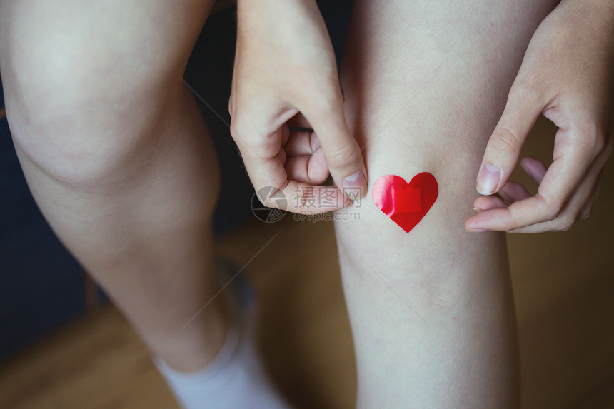 女孩在腿上用红心涂药膏图片