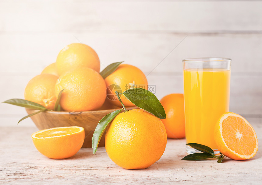玻璃有机新鲜橙汁和浅木底的生橙子图片