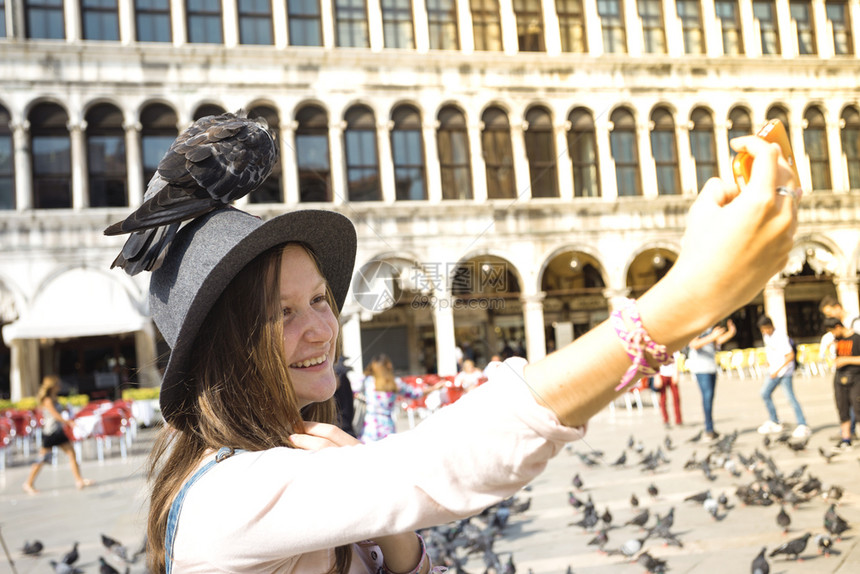 笑着的十几岁女孩与鸽子在广场圣马可维妮丝Italy图片