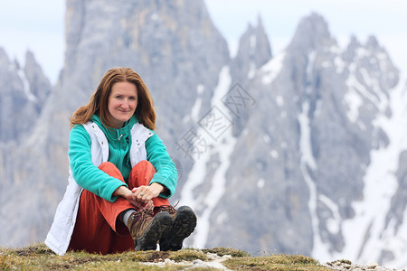 坐在笑的女孩与高岩石山在背景活动高清图片素材