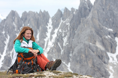 坐在笑的女孩与高岩石山在背景阿尔卑斯山高清图片素材
