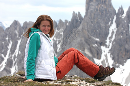 坐在笑的女孩与高岩石山在背景蓝色高清图片素材