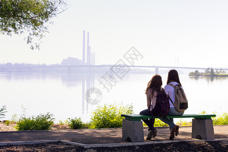 两个十几岁的女孩背坐在德尼伯河的岸上高清图片