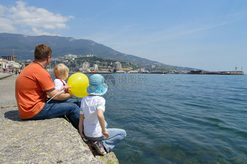 父亲和两个女儿坐在海边图片