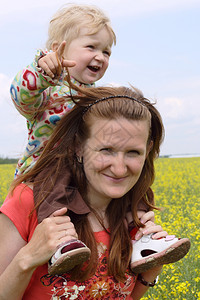 坐在母亲肩上微笑的孩子在田野中行走图片