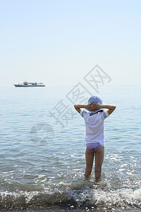 小女孩站在水边看着船图片