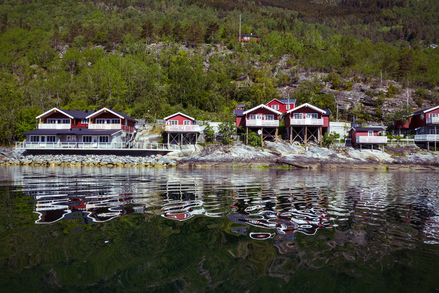 Robuer传统的挪威红木屋站在湖边和远处的山上图片