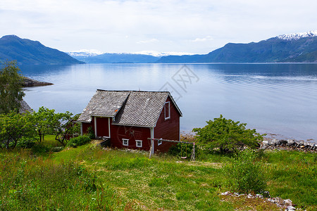 在峡湾海岸的红挪威农村住宅图片