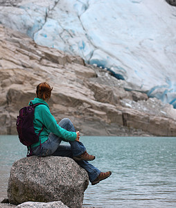 坎布里尔斯坐在石头上看着冰川背景