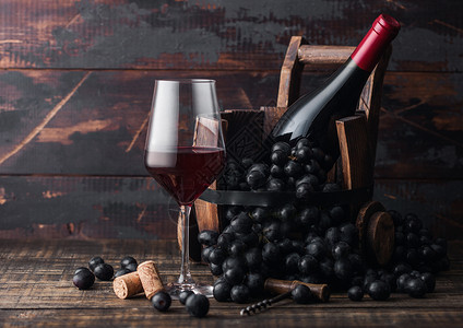 黑色的红葡萄酒和古老的木桶里葡萄酒深黑木质背景红酒保留生命的概念背景图片