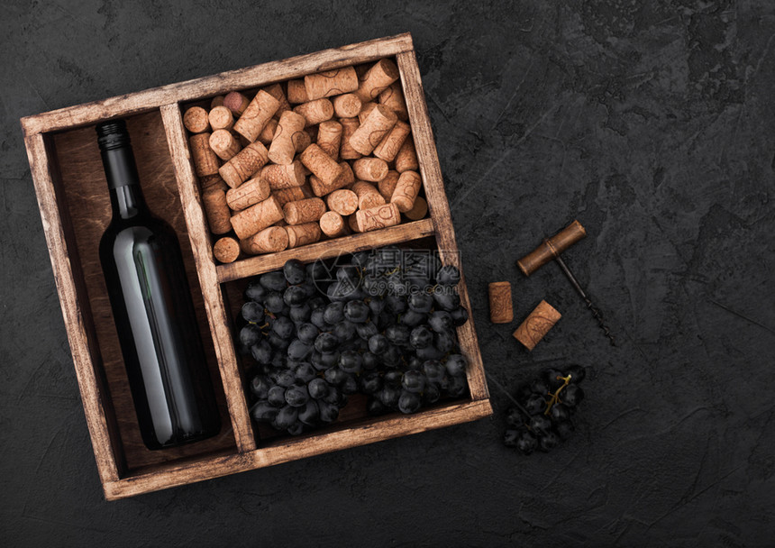 酒瓶红黑葡萄色背景的旧木箱里装有软塞和开瓶器图片