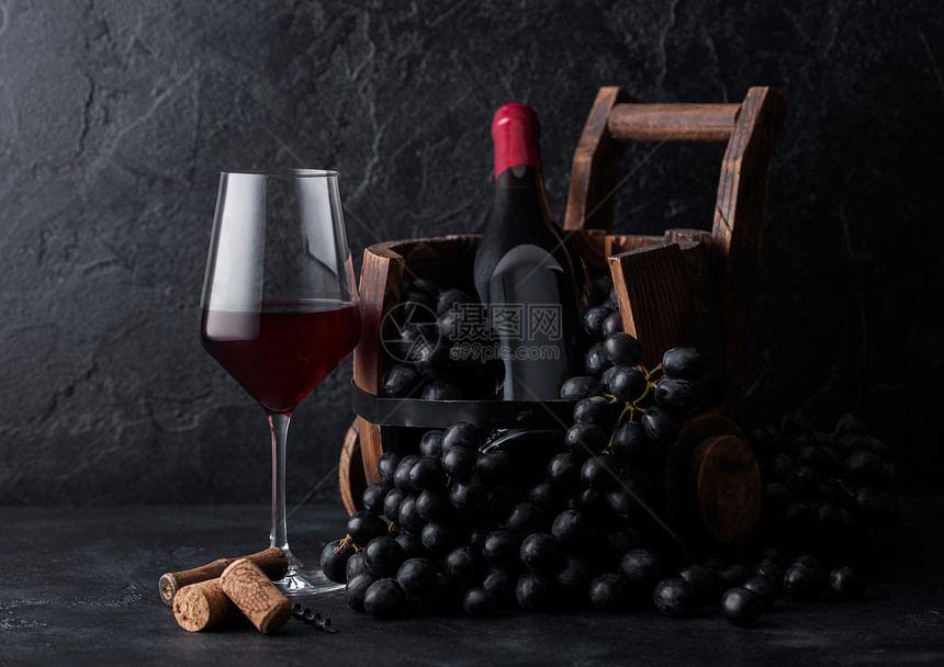 一杯优雅的红酒深葡萄和一瓶酒在古老木桶里图片