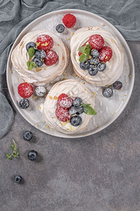 酥皮乳酪脏脏包配有新鲜草莓和蓝的小型帕夫洛娃蛋糕背景