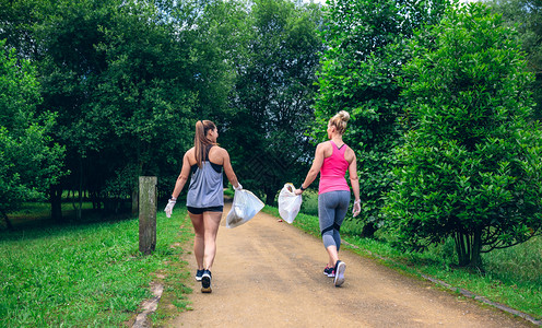 2个女孩背着垃圾袋在作博客2个女孩背着做博客通路高清图片素材