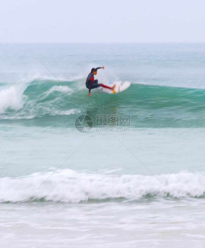 穿湿衣的年轻冲浪手在运动的波上模糊笔式脚步图片