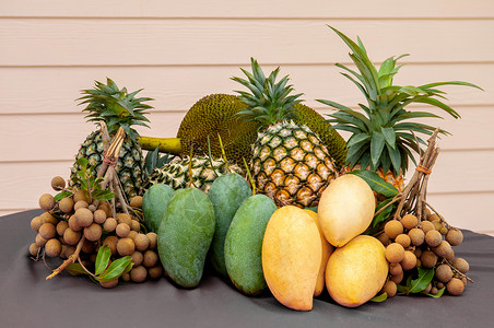 新鲜塔伊热带水果绿色芒黄菠萝长兰餐桌上的胡萝卜有明亮的两边木壁背景图片