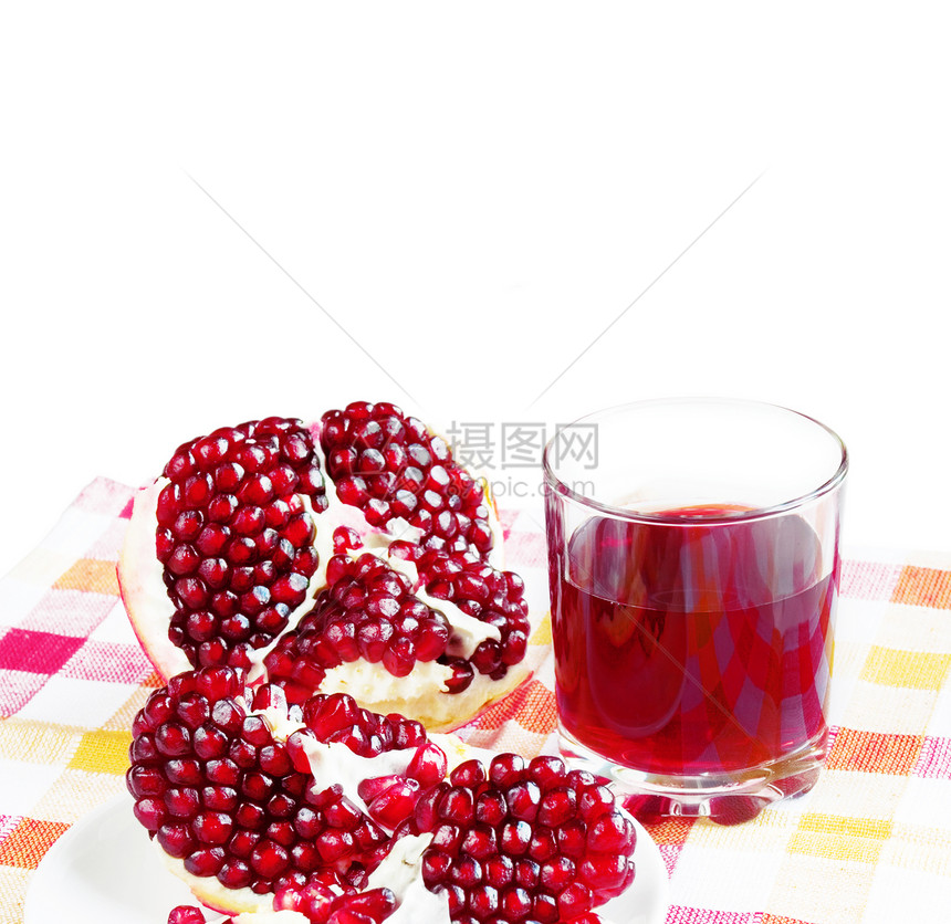 玻璃杯中的石榴汁和餐巾纸上的石榴水果图片