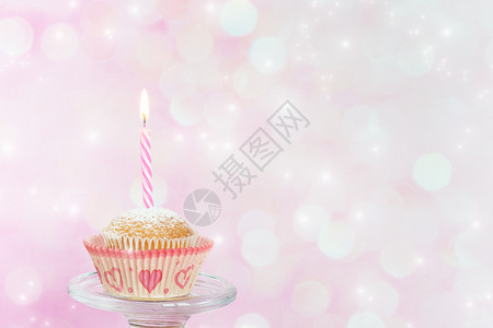 小蛋糕一个粉红背景的烧着蜡烛小纸杯蛋糕图片