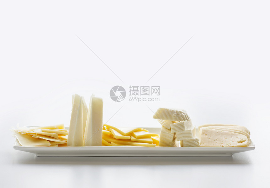 长方形白色瓷板上装满不同品种的奶酪片有复制空间图片