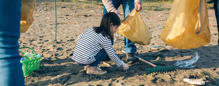 女孩志愿者在海滩上捡垃圾背景图片