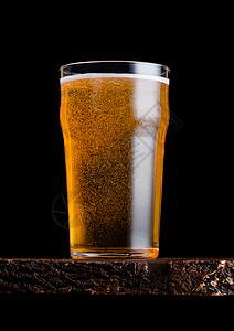 黑色啤酒玻璃啤酒泡沫和在旧木板上黑色背景