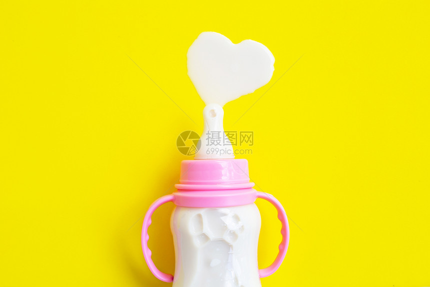 黄色背景的婴儿奶瓶心形状顶视图图片