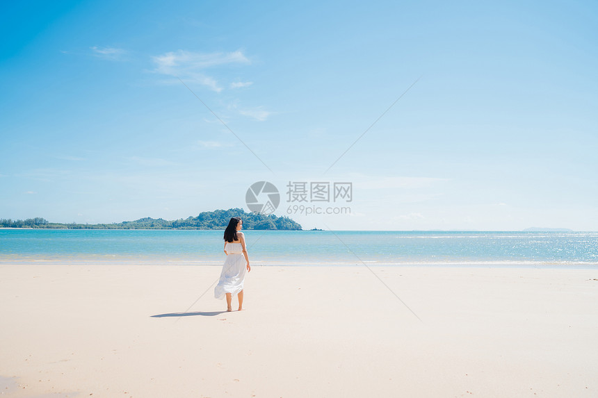 美丽的年轻女在海边的滩散步时快乐地放松图片