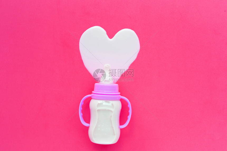 粉红背景的婴儿奶瓶心形状顶视图图片