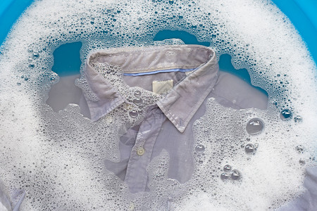灰色衬衫浸泡在粉末洗涤剂水溶解衣服概念中图片