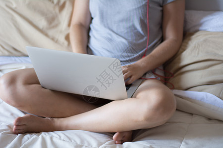 年轻拉丁女在躺家中床上时使用笔记本电脑的肖像概念高清图片素材