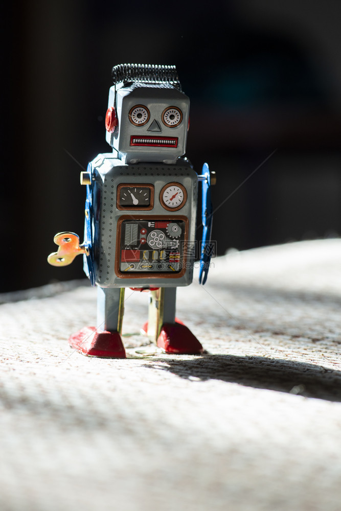 古老的金属蓝色机器人在阳光下的玩具与小型机械器人玩具在布面上行走的远期概念涂漆的眼睛和电子仪表板机械玩具钥匙硬光和阴影图片