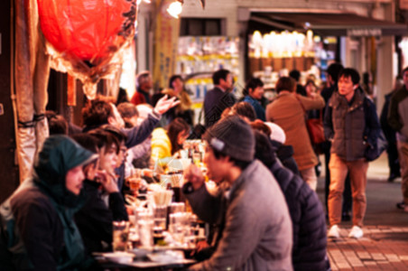 乌尼诺区活跃的繁忙食品街夜生活焦点模糊游客在街边的伊扎卡亚餐厅吃喝背景图片