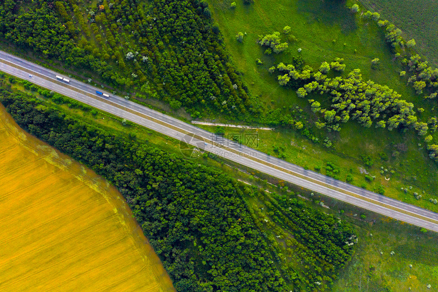 穿越绿色和黄夏季田地的高速公路空中航向图片