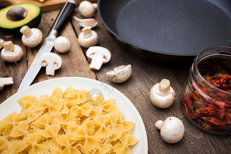 烹饪意大利面的成分意大利面蘑菇蒜洋葱鳄梨奶酪和煎锅图片