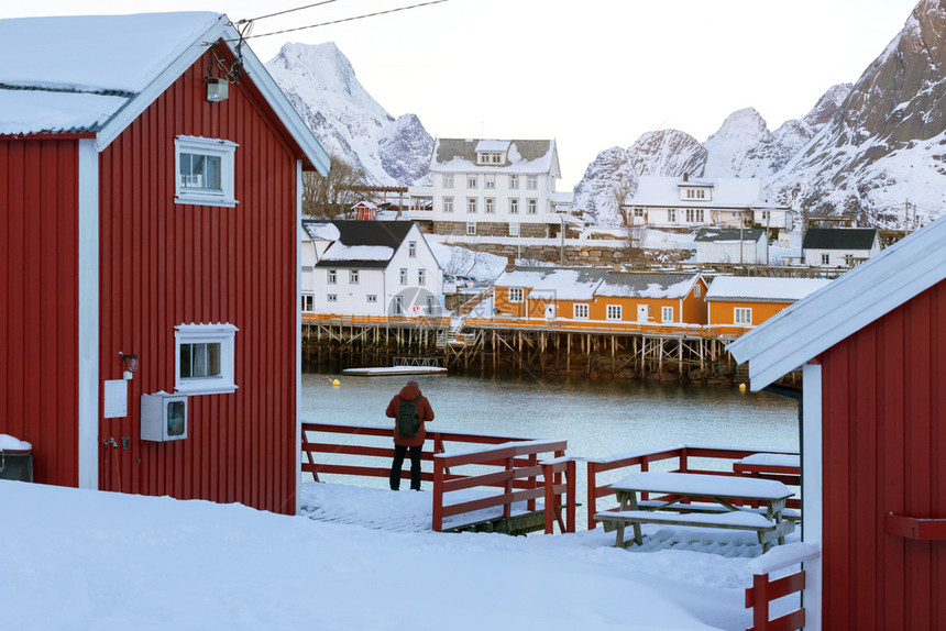 传统的挪威木制屋站在峡湾的岸边和远处山上岛屿北部图片