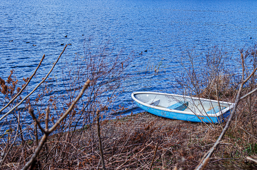 旧的破船被困在川口子湖岸上有干草和树枝图片