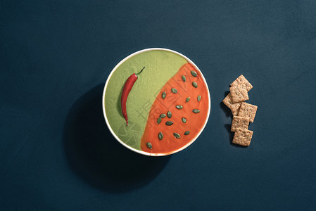 番茄菠菜奶油汤碗里有种子和饼干蓝色背景健康餐前图片