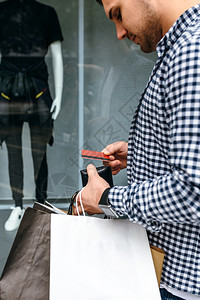 拿着购物袋的年轻人从钱包中拿出信用卡男人拿图片