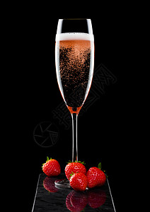 粉红玫瑰香槟的优雅杯子黑色大理石板上的草莓和新鲜果子图片