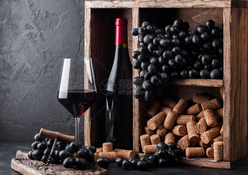 红酒瓶装黑葡萄和古老木箱内用黑石本底的软木瓶装酒美杯黑板上装着软木瓶红酒仍然有生命概念图片