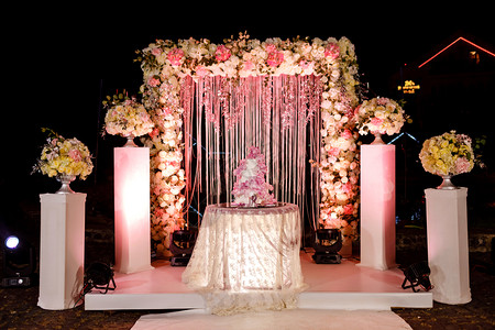婚前装饰餐桌配有结婚蛋糕蜡烛灯光和鲜花餐桌配有结婚蛋糕灯光和鲜花背景图片