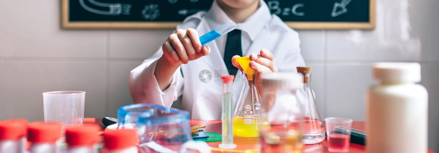 小男孩科学家用化液体对抗粉笔板画有选择地专注于手上严重小男孩用化学液体玩耍图片