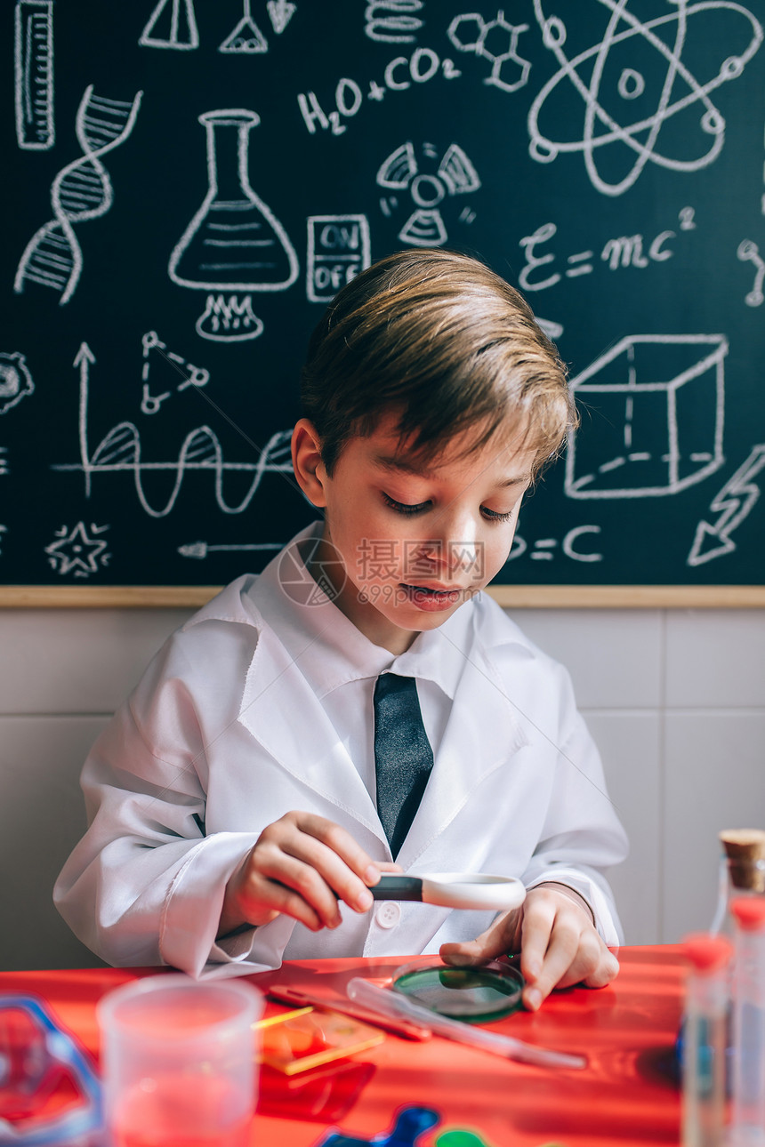 快乐的小科学家肖像看着多彩的化学液体用放大器对着抽画的黑板快乐孩子通过放大镜寻找液体图片