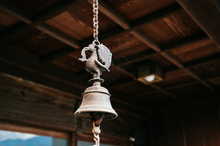古董铜铃挂在木天花板下的金属链上背景图片