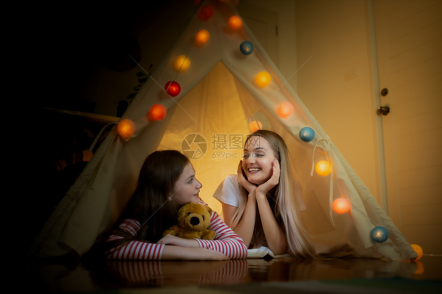 快乐的小女孩和母亲微笑在家里帐篷露营创造思维图片