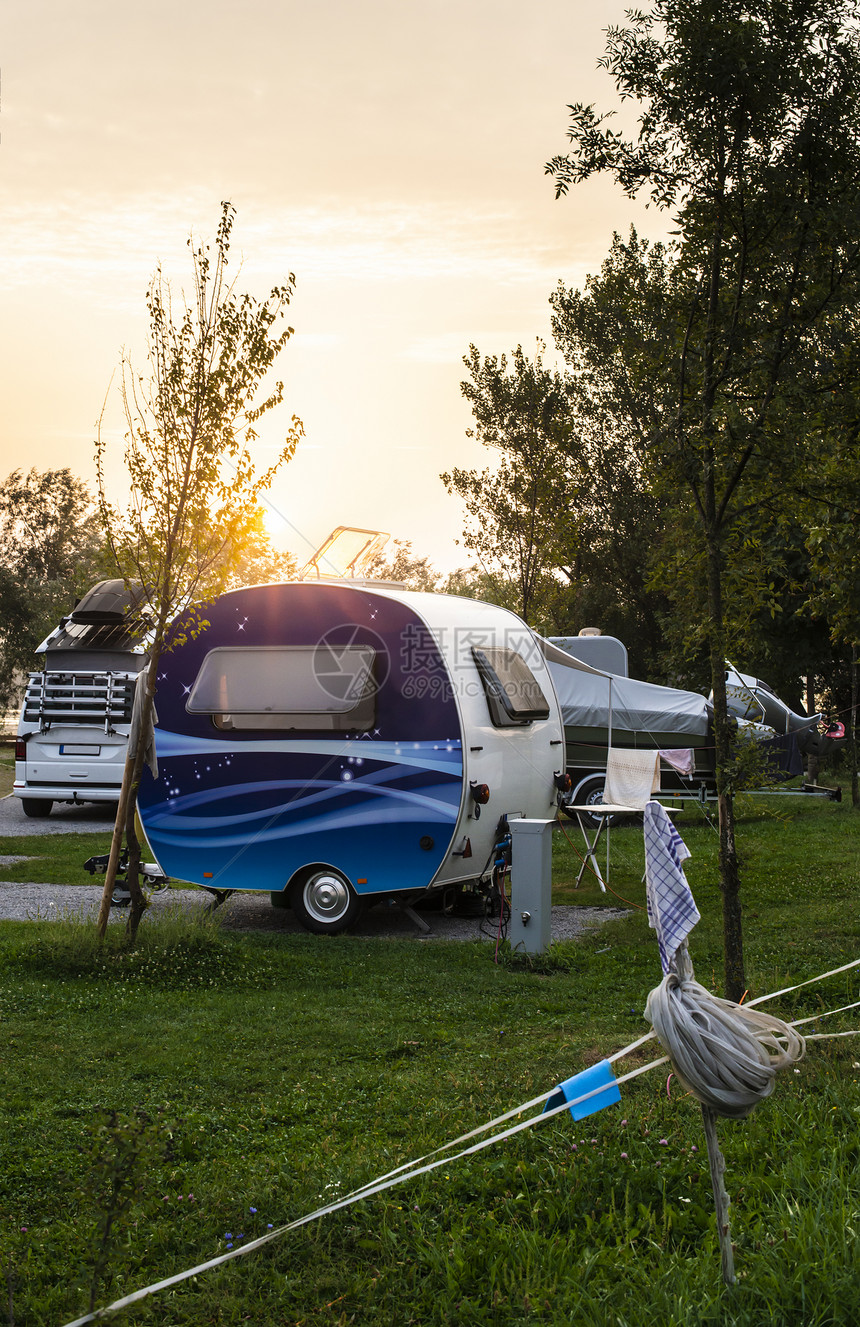 野营的绿色草原上有大篷车和露营者日出早上对露营者进行射线绿草外出旅行的概念和自然界恢复图片